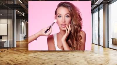 Makeup artist applies pink lipstick . Beautiful woman face. Hand of make-up master, painting lips of young beauty model girl . Make up in process Wall mural