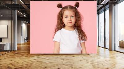 Portrait of cute european little toddler girl over pink background. Looking at camera. Child model in white T-shirt. Advertising childrens products Wall mural