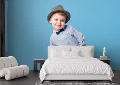 Portrait of happy joyful  little boy isolated on blue background. Toddler child in hat and fashionable suit smiling and have a fun  Wall mural