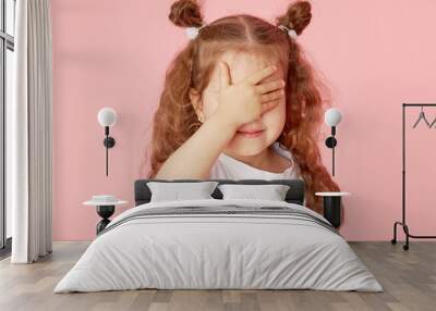 Portrait of surprised cute little toddler girl child over pink background. Looking at camera. Points hands to the left side. Advertising childrens products Wall mural