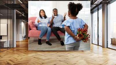 African child girl hiding red flowers for surprise her father and mother behind her back in the home Wall mural