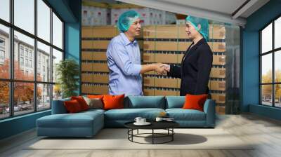 businessman meeting and shaking hands with businesswoman in the beverage factory Wall mural