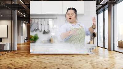 down syndrome teenage girl throwing and sprinkling white flour for making a bread or cooking food in a kitchen Wall mural