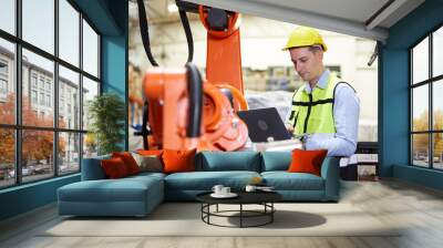 factory worker or engineer holding a laptop computer and controlling robot machine in the factory Wall mural