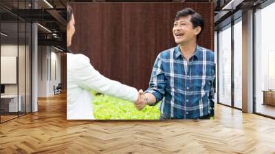 male farmer shaking hands businesswoman together in hydroponic farm Wall mural