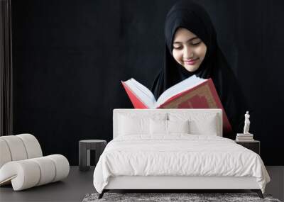 muslim girl reading a holy book quran on black background Wall mural