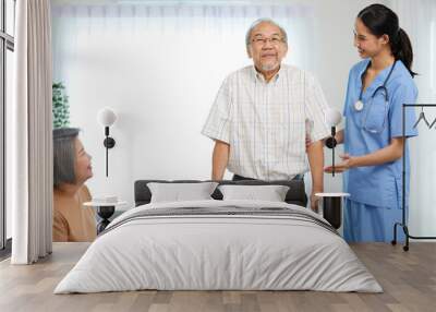 nurse or caregiver helping senior man walking with a walker and senior woman support him at home Wall mural