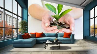 Saving money concept and woman’s hands holding money coin with growing plant  Wall mural