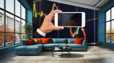 Businessman hand holding mobile phone  with empty screen with stock market graph background Wall mural