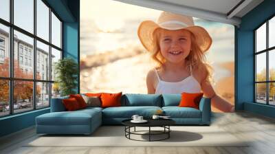 A happy little girl in white dress with a hat joyfully having a great time on a sunny beach during a day, enjoy the summer, adorable little girl on the beach. Wall mural