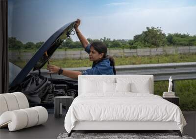 Young Indian girl on the road trying to fix her car after it's breakdown on road Wall mural