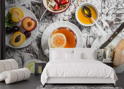 Breakfast or snack table. Lemon tea, fresh fruit, yogurt with granola, blue cheese, biscuits. On a light background Wall mural