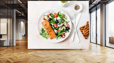 Healthy balanced lunch - grilled red fish fillet salmon and tomatoes, cucumbers, olives, feta Greek salad on a light background, top view Wall mural