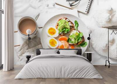 Womens cozy breakfast in bed still life - coffee, avocado sandwiches, boiled egg and tangerine on a light background, top view. Morning inspiration plan Wall mural