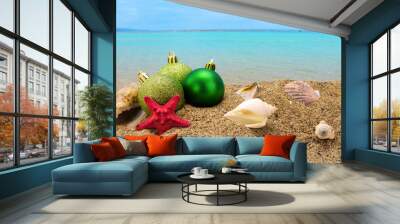 Christmas balls and shells on sand with summer sea background Wall mural