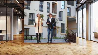 Meeting of business partners and negotiations between young businesswoman and manager on background of new residential apartment building Wall mural