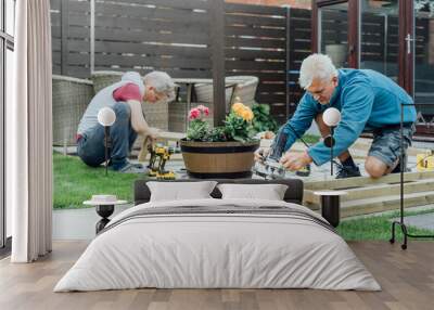 Adult son and father carpenter working together, handle wooden timbers in the garden. Patio construction by your own. DIY, Do it yourself. Home renovation, improvement, refurbishment. Selective focus Wall mural