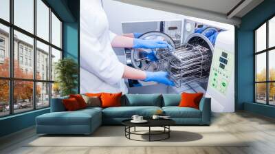 Dentist assistant's hands get out sterilizing medical instruments from autoclave. Selective focus Wall mural