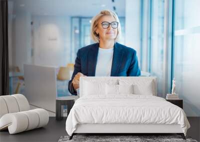 Smiling middle-aged business woman having healthy lunch at working place or business cafe, with laptop during her break. Balanced diet lunch box. Healthy eating habits and well-being. Selective focus Wall mural