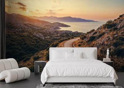 Blue car drives up a winding coastal mountain road with a stunning golden hour sunset in the background Wall mural