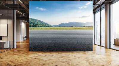 Empty asphalt road is leading to beautiful green mountains in the distance with under blue sky background Wall mural