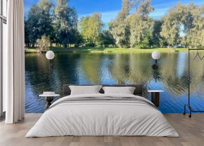 Beautiful blue lake in the park, sky and trees reflection on the lake surface Wall mural