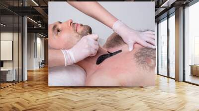 Closeup of male chest with hair and wax. Professional shugaring master in gloves makes depilation to a young man in the salon Wall mural