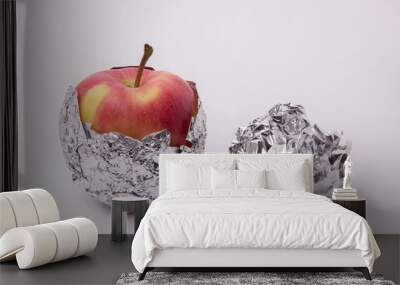 several red and yellow ripe apples, wrapped in foil on a white b Wall mural