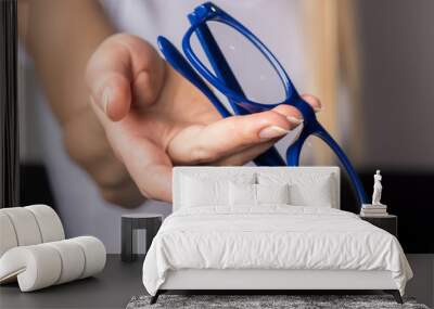 Soft contact lens and blue-rimmed eye glasses in female hands. Wall mural