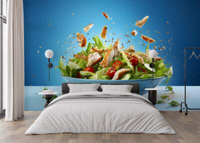 Chicken and vegetables salad falling in bowl on blue background Wall mural