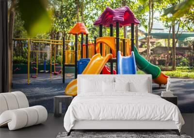 Colorful kid playground with a slide and swing set on yard in the park Wall mural