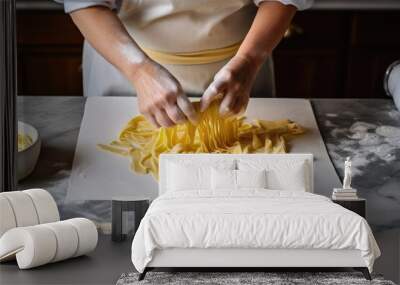 Crop anonymous female cook preparing traditional Italian rolled fresh tagliatelle pasta on marble counter in kitchen Wall mural