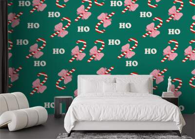 Festive Christmas pattern with candy canes, pink bows, and ho ho ho text on a green background. Holiday design for wrapping paper, wallpaper, textile, poster background, etc.  Wall mural