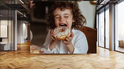 Kid excitedly eating donut at birthday party Wall mural