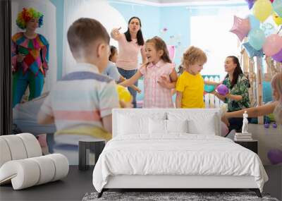 Active kids having fun and playing with parents with multicolored balloons in daycare Wall mural