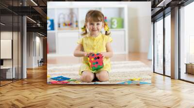 Child preschooler girl plays logical toy learning shapes and colors at home or nursery Wall mural