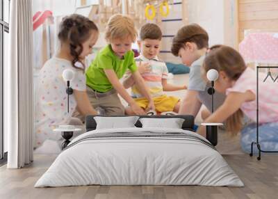 Children sit rounds on floor in kindergarten. Preschool kids learning how to tell time from clock and set the hands in the correct position. Real people, moments, authentic situations Wall mural