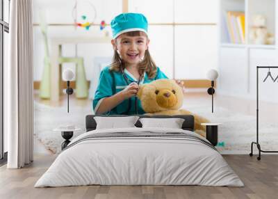 Cute kid girl playing doctor with plush toy at home Wall mural