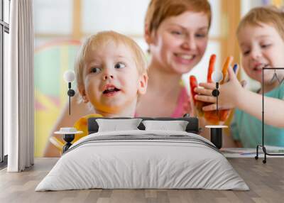 Cute woman playing and painting with children Wall mural