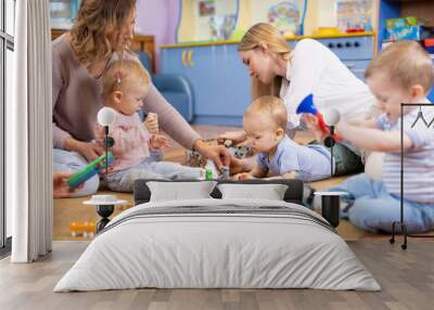 Friends with children toddlers playing on the floor in montessori centre Wall mural