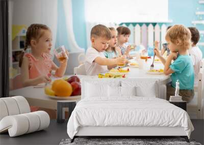 Group of children eating healthy food in day care centre Wall mural