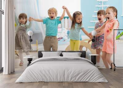 Group of happy kindergarten children jumping raising hands while having fun in entertainment center Wall mural