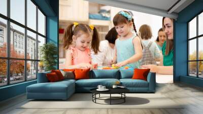 Group of kids with teacher playing with developmental toys in kindergarten Wall mural