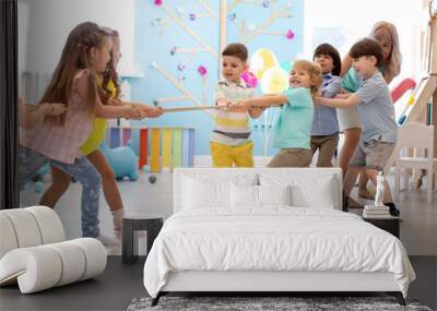 group of preschool kids play and pull rope together in daycare Wall mural