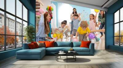 Happy children and their parents entertain and have fun with color balloons on birthday party Wall mural