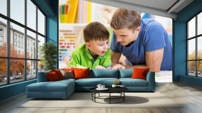 kid boy and his father read a book on floor at home Wall mural