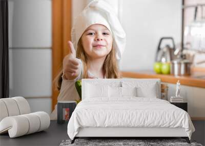 kid girl weared as cook with vegetables at kitchen Wall mural