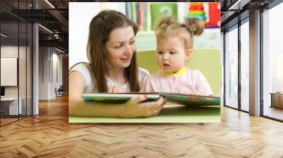 Mother reading with her daughter at table Wall mural