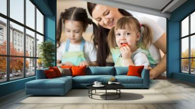 Positive woman and her kids preparing lunch in the kitchen Wall mural