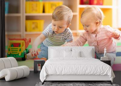 Preschool boy and girl playing on floor with educational toys. Children toddlers at home or daycare. Wall mural